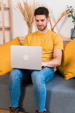 Cheerful man using laptop on sofa Stock Photos
