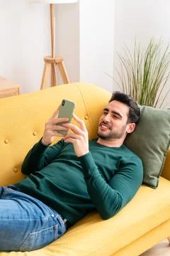 Cheerful man using smartphone on sofa Stock Photos
