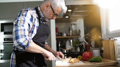 Cheerful mature man in kitchen preparing dish Stock Footage 103287203