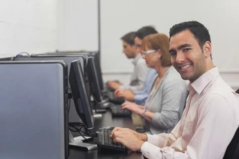 Cheerful mature student sitting in computer class Stock Photos
