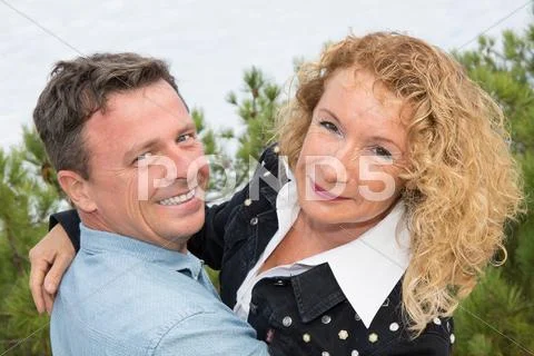 Cheerful mature woman embracing smiling man Stock Photos
