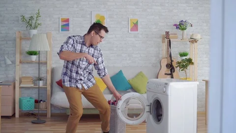 Cheerful middle-aged man engaged in household chores washes things and dances Stock Footage 108612308