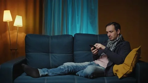 Cheerful middle aged man sitting on the sofa using phone modern apartment Stock Footage 189885765