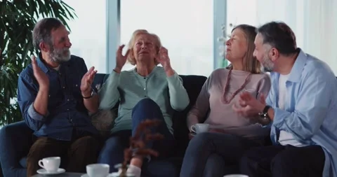 Cheerful middle-aged married couple talking to their elderly parents sharing Stock Footage 148286200