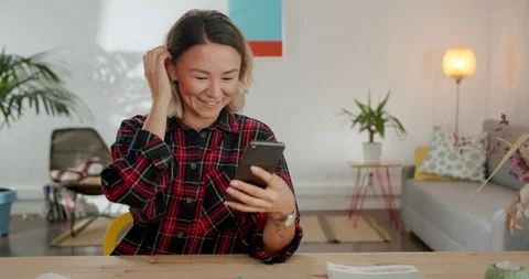 Cheerful millennial girl using mobile device to stay online in internet at Stock Footage 120948271