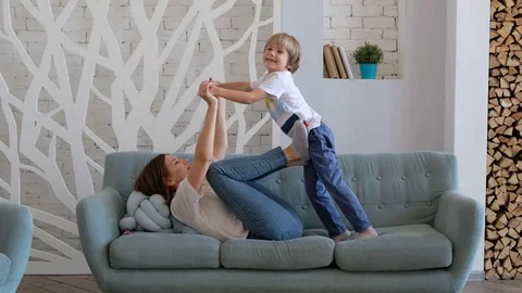 Cheerful mom is playing with her son by lifting him up like a plane. Child Stock Footage 116656982