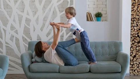 Cheerful mom is playing with her son by lifting him up like a plane. Child Vídeos de archivo 116657007