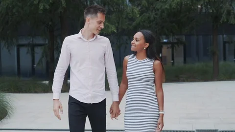 Cheerful multiethnic couple walking down the street, hugging and kissing Stock Footage 119640742