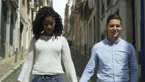 Cheerful multiethnic couple walking down street Stock Footage 132936290