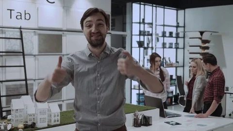 Cheerful office worker at desk doing thumb up sign and smiling. Real workplace Stock Footage 84725989