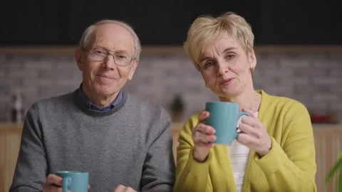 Cheerful old married couple is looking at camera and waving hands to welcome Stock Footage 153532629