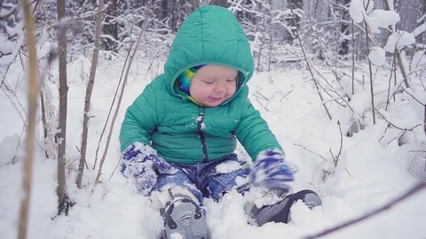 Cheerful one year boy is sitting in the winter forest and laughs. created with Видео 83462871