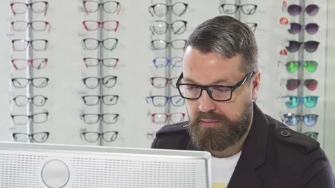Cheerful optometrist assisting customers while working on a computer Stock Footage 311647617