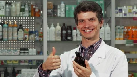 Cheerful pharmacist showing thumbs up while working at the drugstore Stock Photos