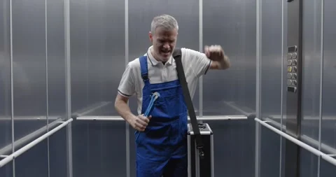 Cheerful plumber dancing and singing in the elevator Stock Footage 308916292