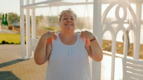 Cheerful plus size senior rotating shoulders in outdoor park. fitness and Vídeo Stock 340992728