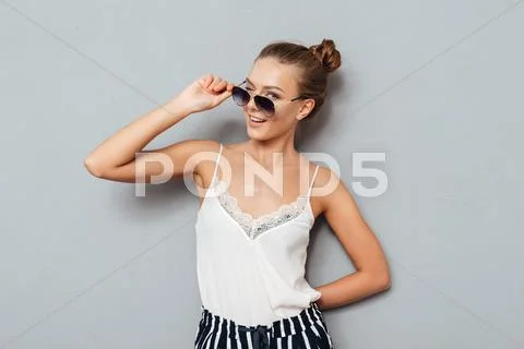 Cheerful pretty young woman holding sunglasses and winking Stock Photos