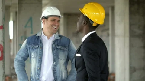 Cheerful professional construction manager and afro businessman talking and 스톡 동영상 114995992