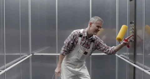 Cheerful professional painter dancing and singing in the elevator Stock Footage 308916307