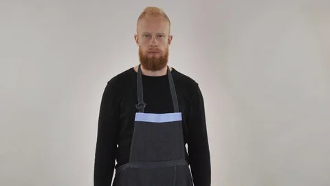 A cheerful red-haired chef with a beard stands with a chef's spoon and smiles. Stock Footage 81776128