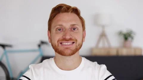 Cheerful red haired young man smiling at camera on video call from home Stock Footage 312204199