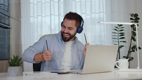 Cheerful remote worker in earphones using smartphone and enjoying music indoors Stock-Footage 261659722