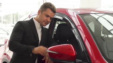 A cheerful salesman points to the excellent quality of the car Video stock 80968172