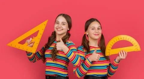 Cheerful school students hold math tool of triangle and protractor Foto stock