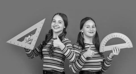 Cheerful school students hold math tool of triangle and protractor Stock Photos