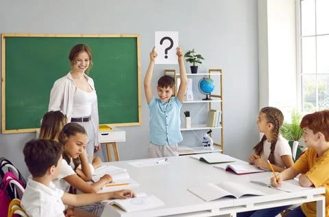 Cheerful schoolchildren solve logical problems together with teacher in creative Foto stock