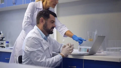 Cheerful scientists working on laptop together Stock Footage 80359481