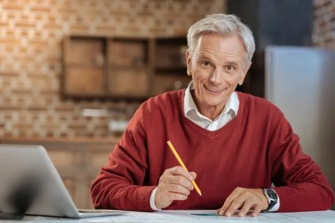 Cheerful senior engineer posing while drawing blueprint Stock Photos