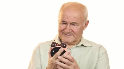 Cheerful senior man smiling at the camera while holding an alarm clock Stock Footage 311982769