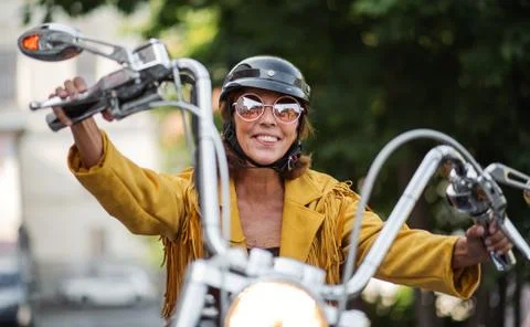 Cheerful senior woman traveller with motorbike in town. Stock Photos