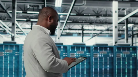 Cheerful server room engineer troubleshooting backend operations using tablet 動画素材 311897648