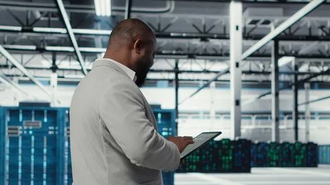 Cheerful server room engineer troubleshooting backend operations using tablet Stock Photos