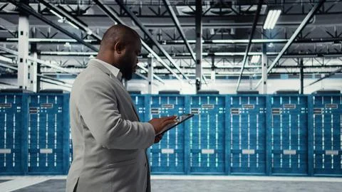 Cheerful server room engineer troubleshooting backend operations using tablet Stock Photos