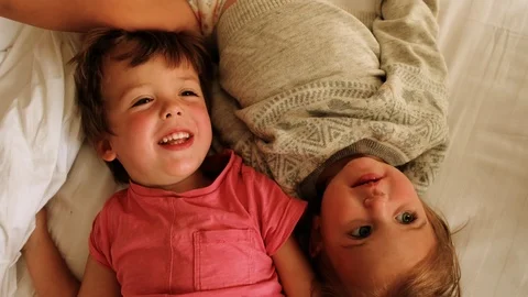 Cheerful siblings lying on bed Stock Footage 125286242