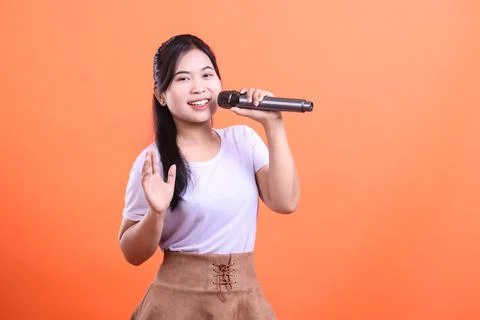 Cheerful singer with microphone on orange background Stock Photos