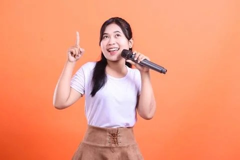 Cheerful singer with a microphone pointing up Stock Photos