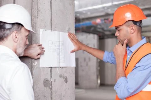Cheerful skilled builders are solving construction problems Stock Photos
