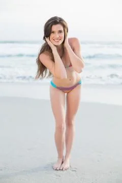 Cheerful slim brown haired model in coloured bikini posing holding her hair Stock Photos