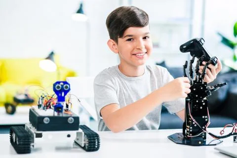 Cheerful smart boy testing his humanoid robotic hand Stock Photos