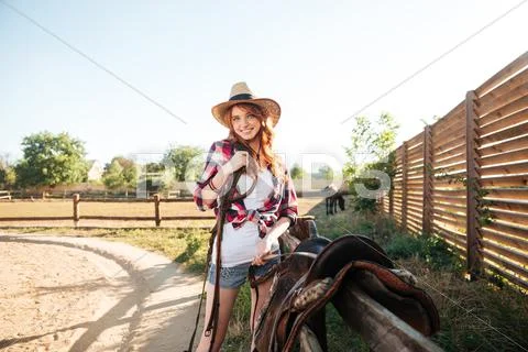 Cheerful smiling cowgirl preparing horse saddle for a ride Stock Photos