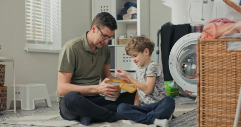A cheerful smiling dad puts his house in order with hardworking son. The men sit Stockbeeldmateriaal 200847125