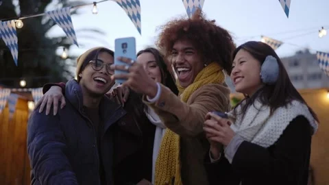 Cheerful smiling multi-ethnic group of four friends shooting outdoor video for Stock Footage 236573727