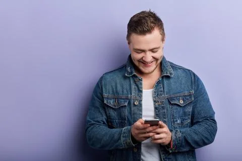 Cheerful smiling young man typing message, sending sms, e-mail Stock Photos