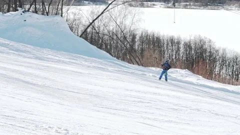 Cheerful snowboarder climbs using a T-bar lift and performs a 180 trick. 動画素材 157550939