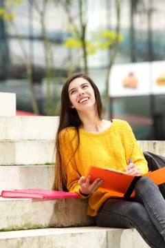 Cheerful student sitting on steps with notebook Stock Photos