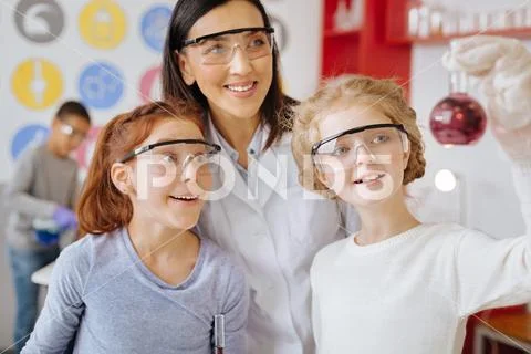 Cheerful students and teacher checking for sediment in flask Stock Photos